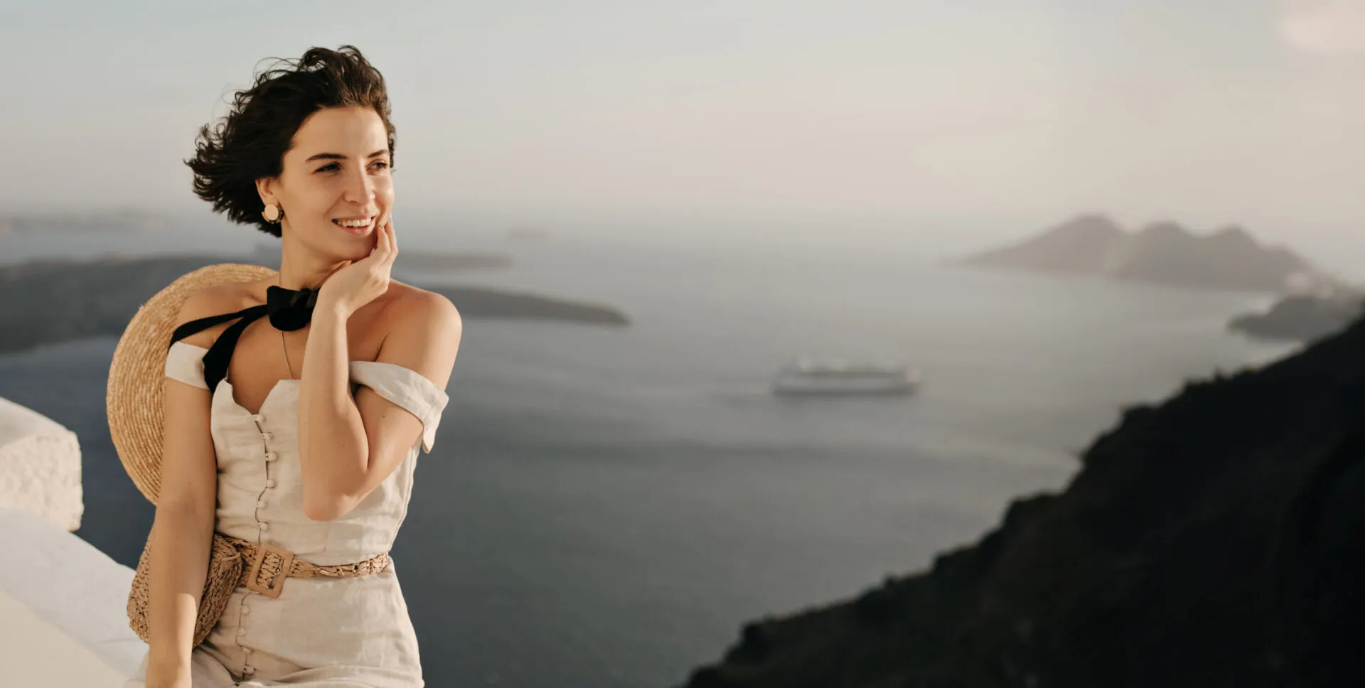 Woman smiling on a whitewashed terrace high above the sea and distant islands
